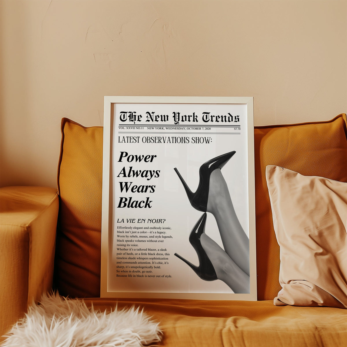 Two pairs of black heels mock newspaper print in a white frame leaning on a mustard velvet sofa