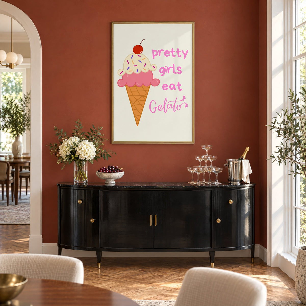 Pretty girls eat Gelato cone print in a brass frame on a terracotta wall above a black buffet with a champagne tower