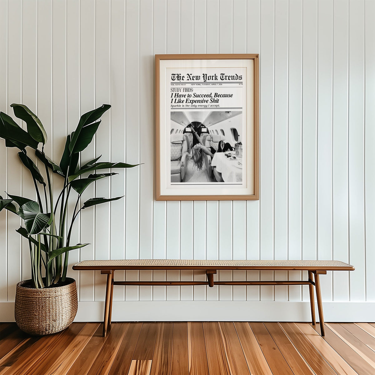 Woman with champagne in private jet mock newspaper print in a wood frame with a white mat above a cane bench