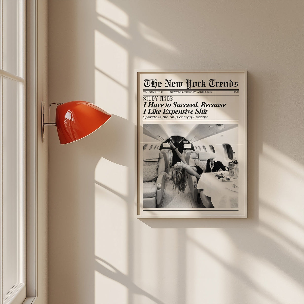 Woman with champagne in private jet mock newspaper print in a white frame on a sunlit wall beside a red sconce
