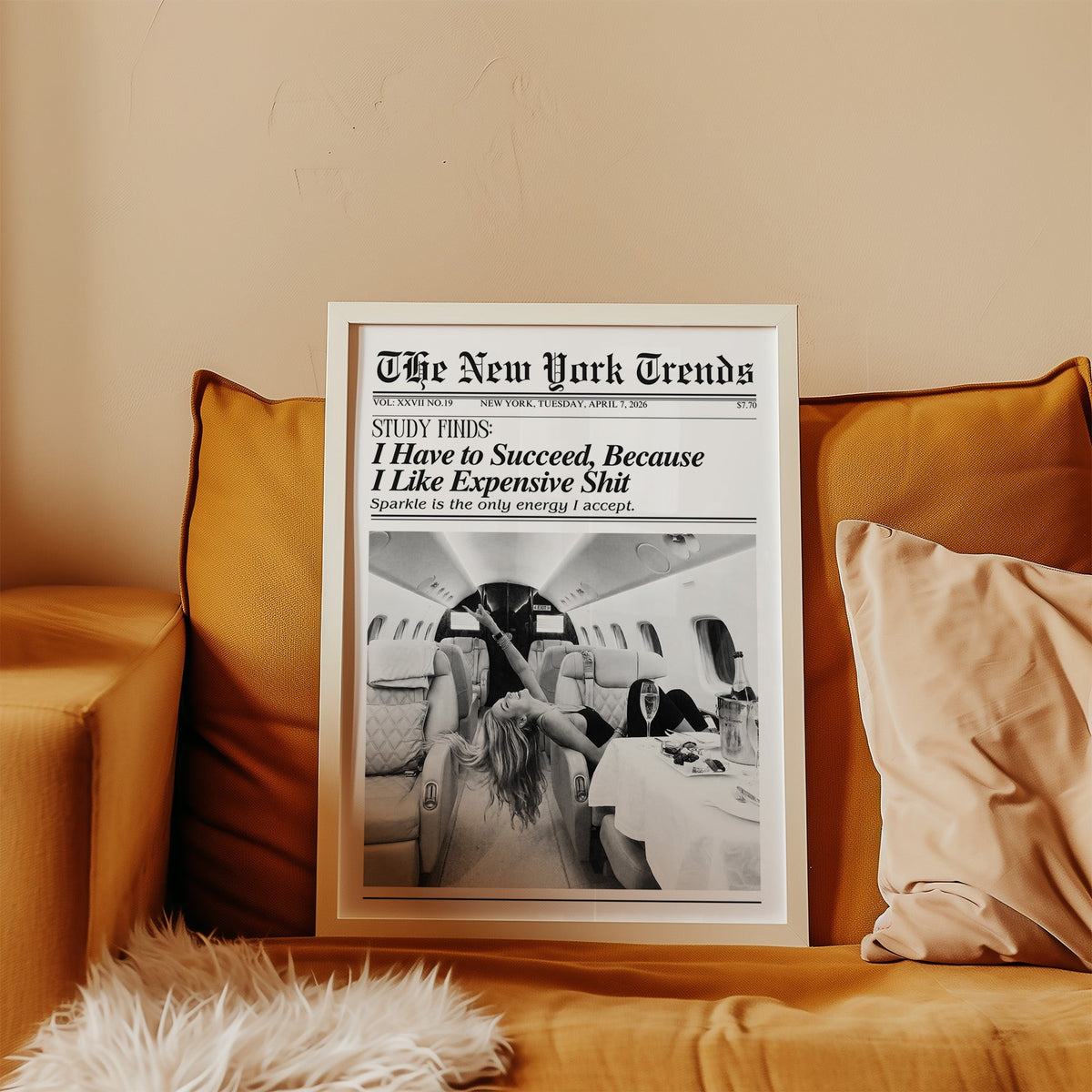 Woman with champagne in private jet mock newspaper print in a white frame leaning on a mustard velvet sofa