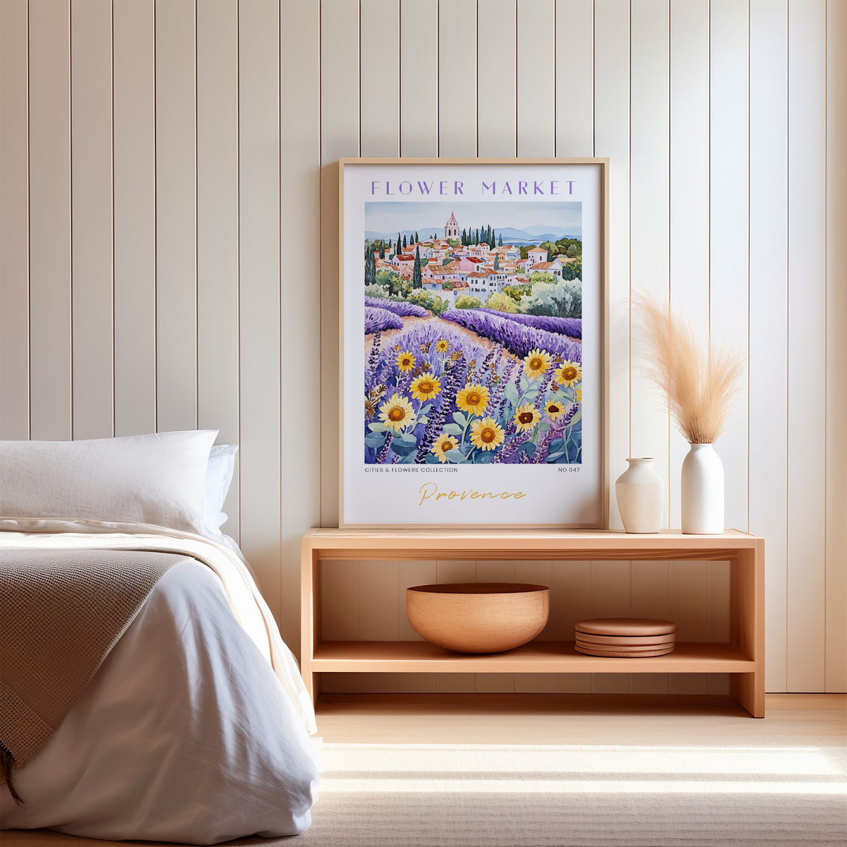 Provence flower market print in an oak frame on a wood bench against a white shiplap bedroom wall with pampas grass