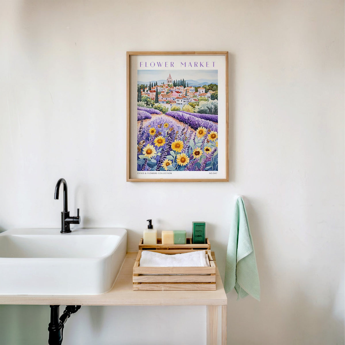Provence flower market print in an oak frame above a white bathroom sink with folded towels