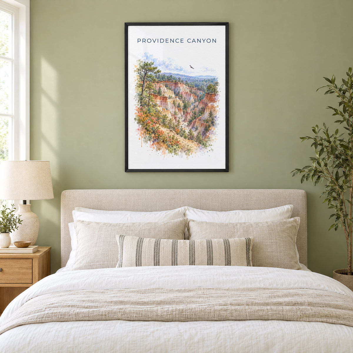 Providence Canyon State Park watercolor print in a black frame above an upholstered headboard in a sage green bedroom