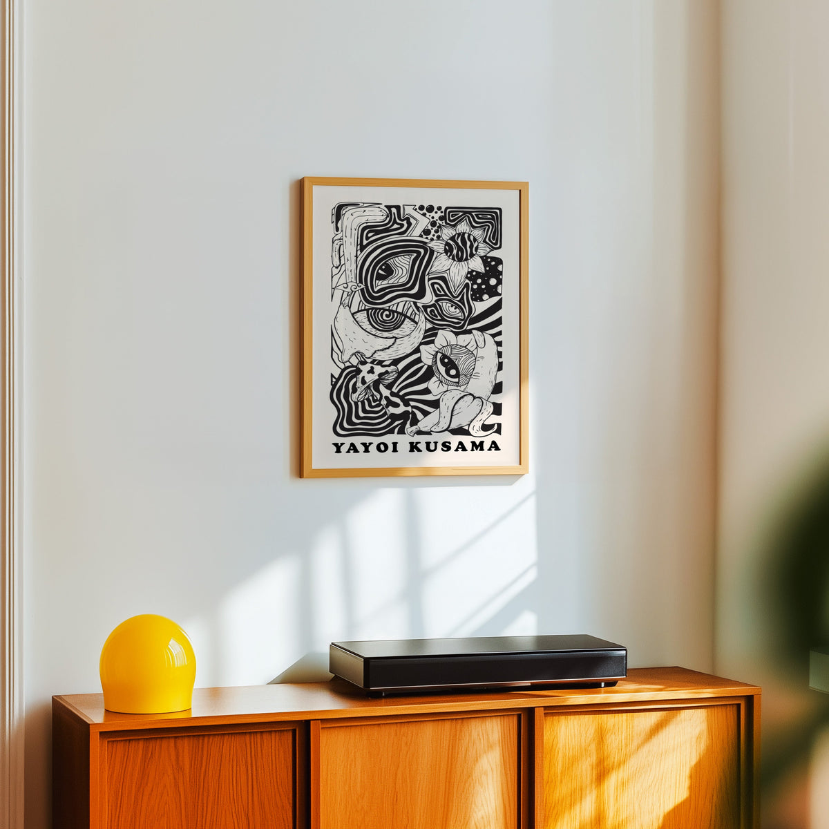 Yayoi Kusama inspired psychedelic eyes and mushroom print in an oak frame over a teak sideboard with a yellow lamp
