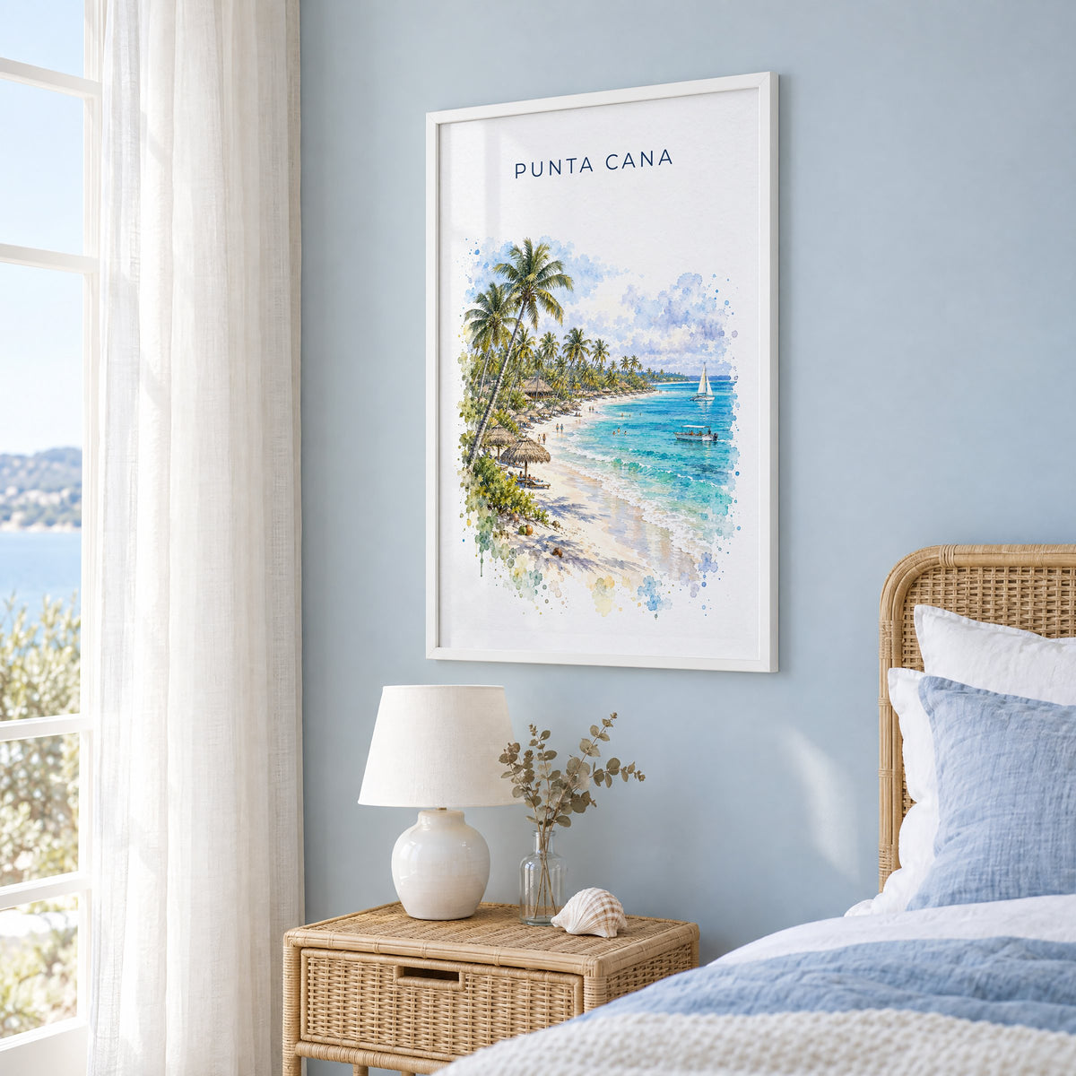 Punta Cana watercolor print in a white frame on a pale blue wall beside a rattan bed in a coastal bedroom