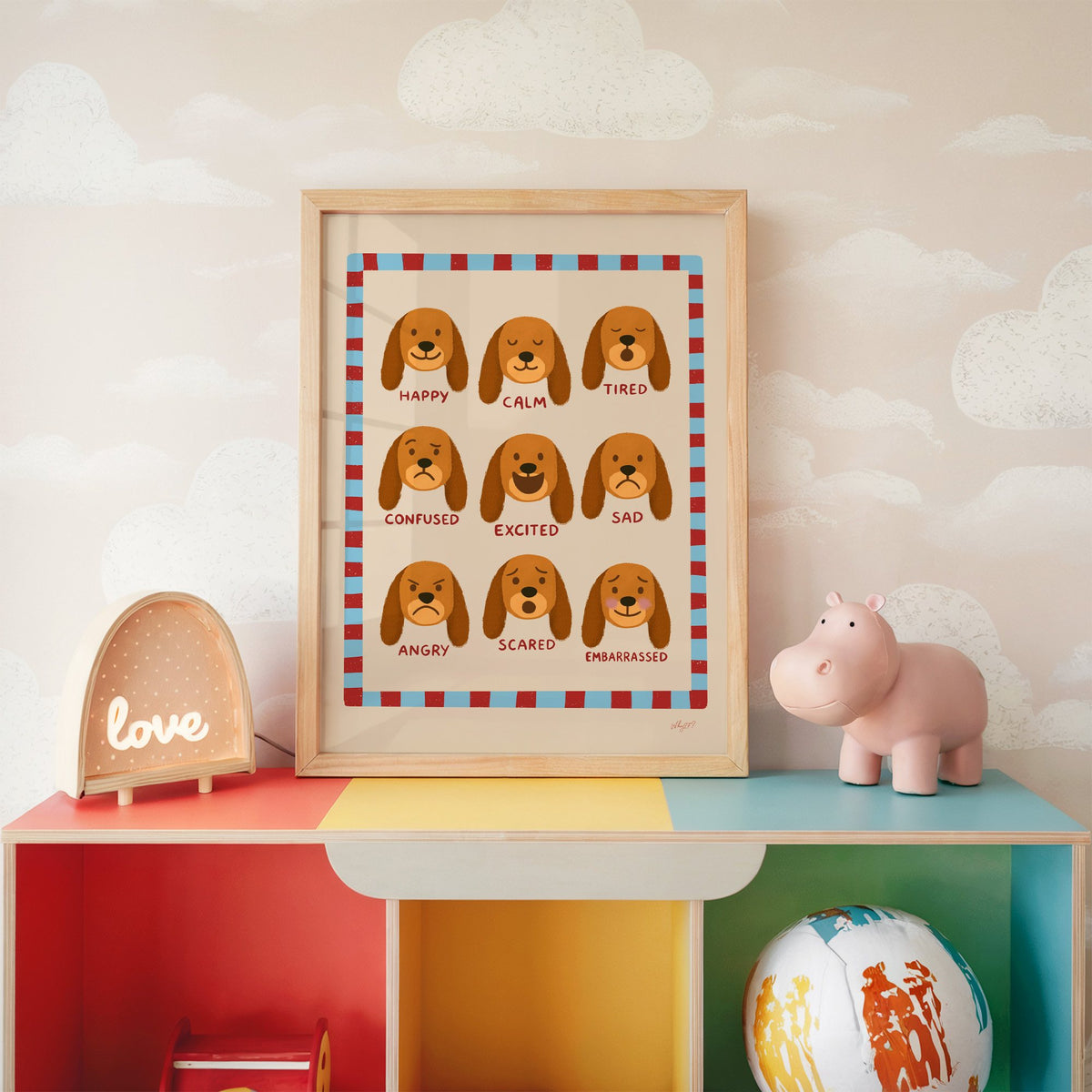 Puppy feelings chart nursery print in an oak frame on a rainbow toy shelf against cloud wallpaper