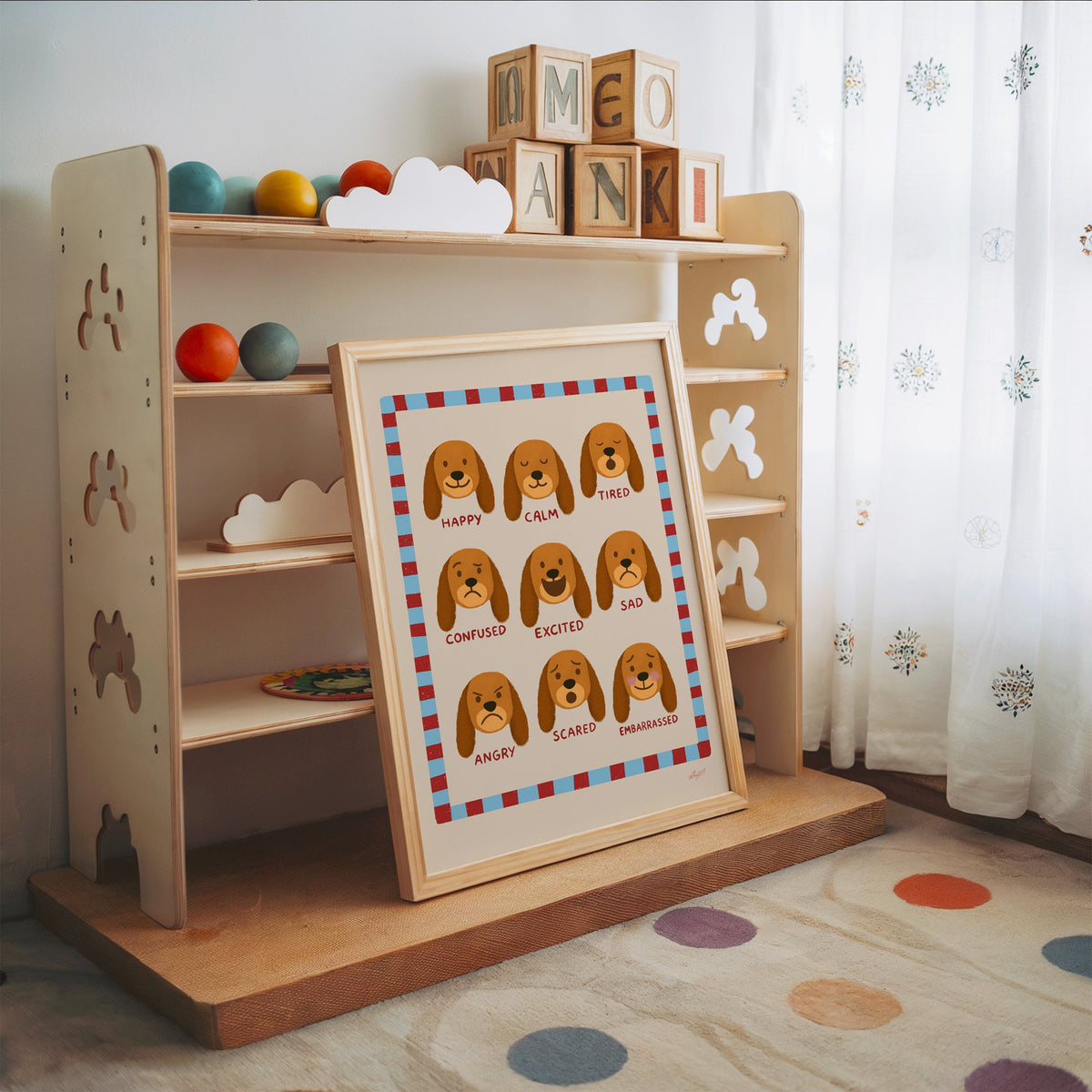 Puppy feelings chart nursery print in an oak frame leaning on a toy shelf with wooden letter blocks