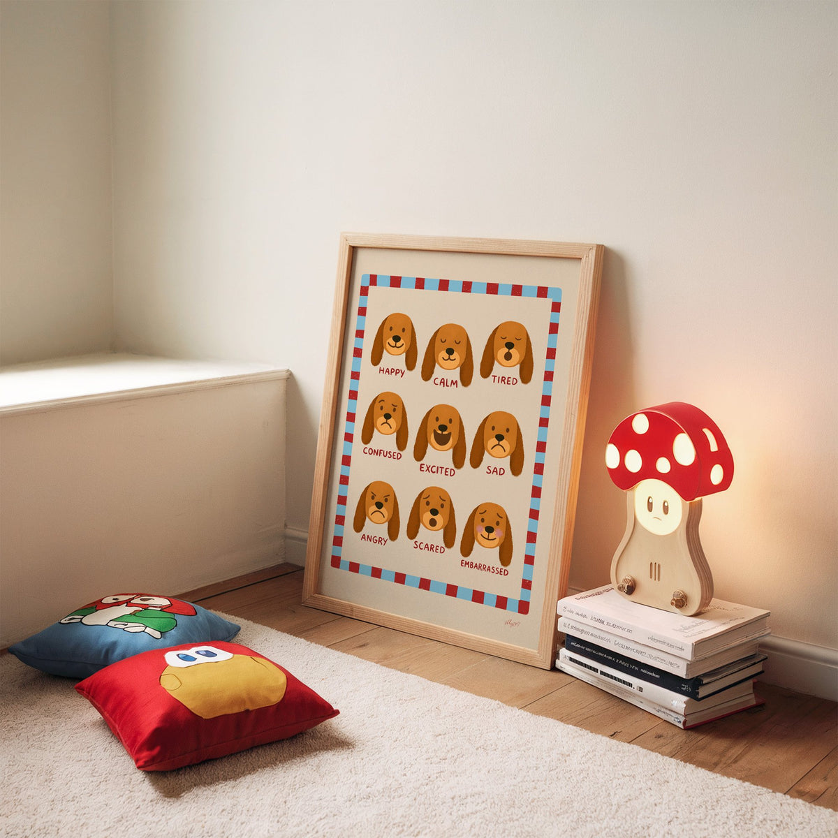 Puppy feelings chart nursery print in an oak frame leaning on a rug beside a mushroom lamp and floor cushions