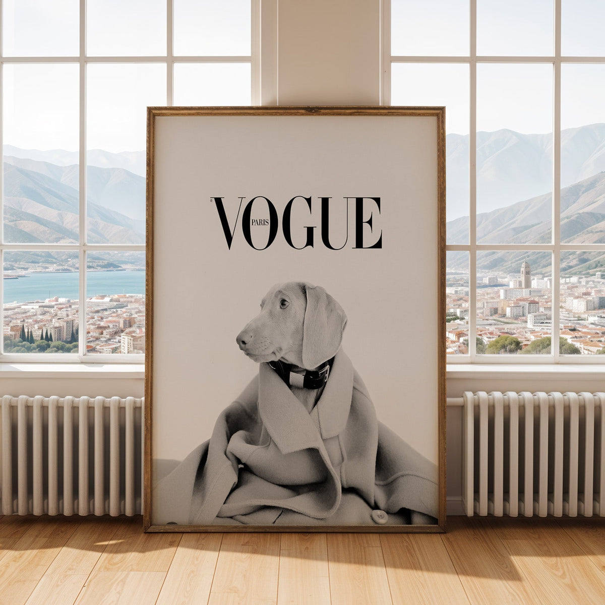 Puppy in oversized wool coat magazine cover print shown in an antique gold frame by tall windows with a sea view