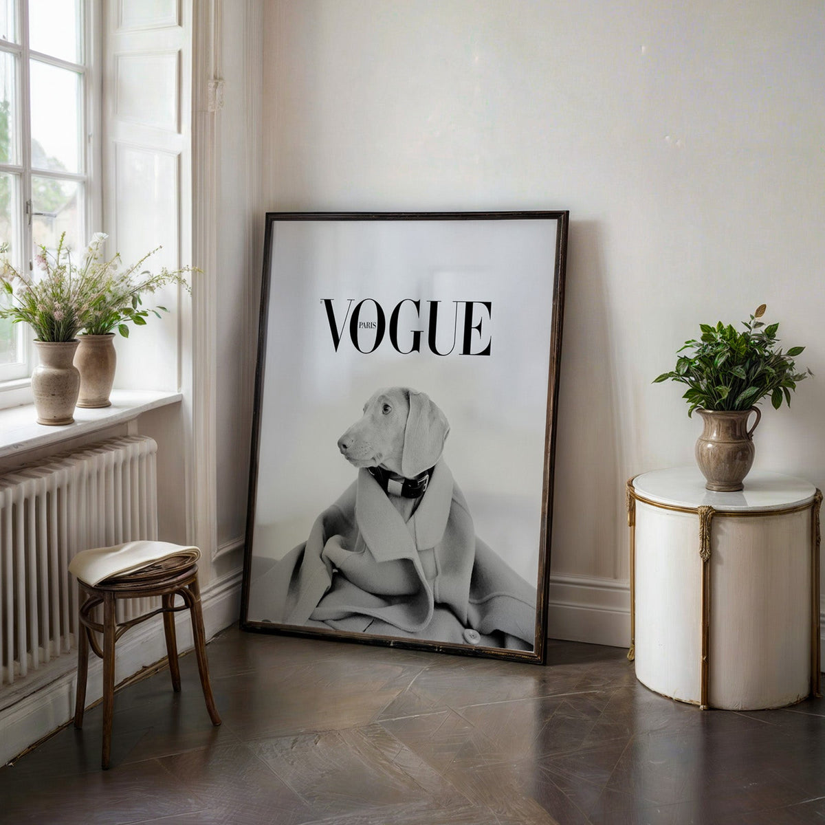 Puppy in oversized wool coat magazine cover print in a black frame on a dark stone floor beside a white side table