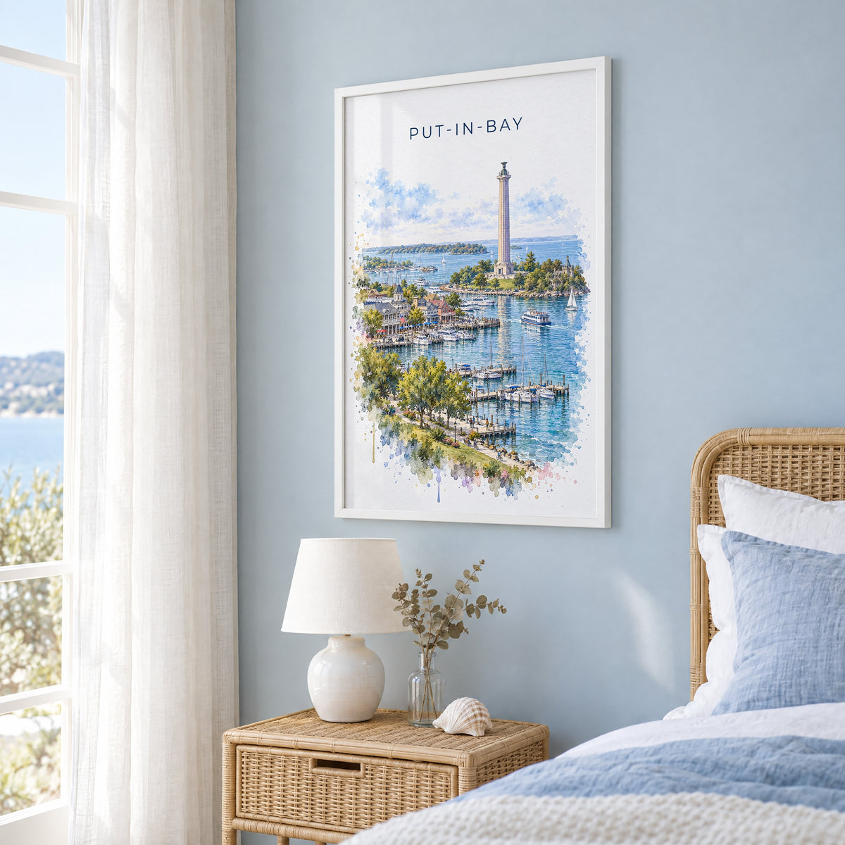 Put-in-Bay watercolor print in a white frame on a pale blue wall beside a rattan bed in a coastal bedroom