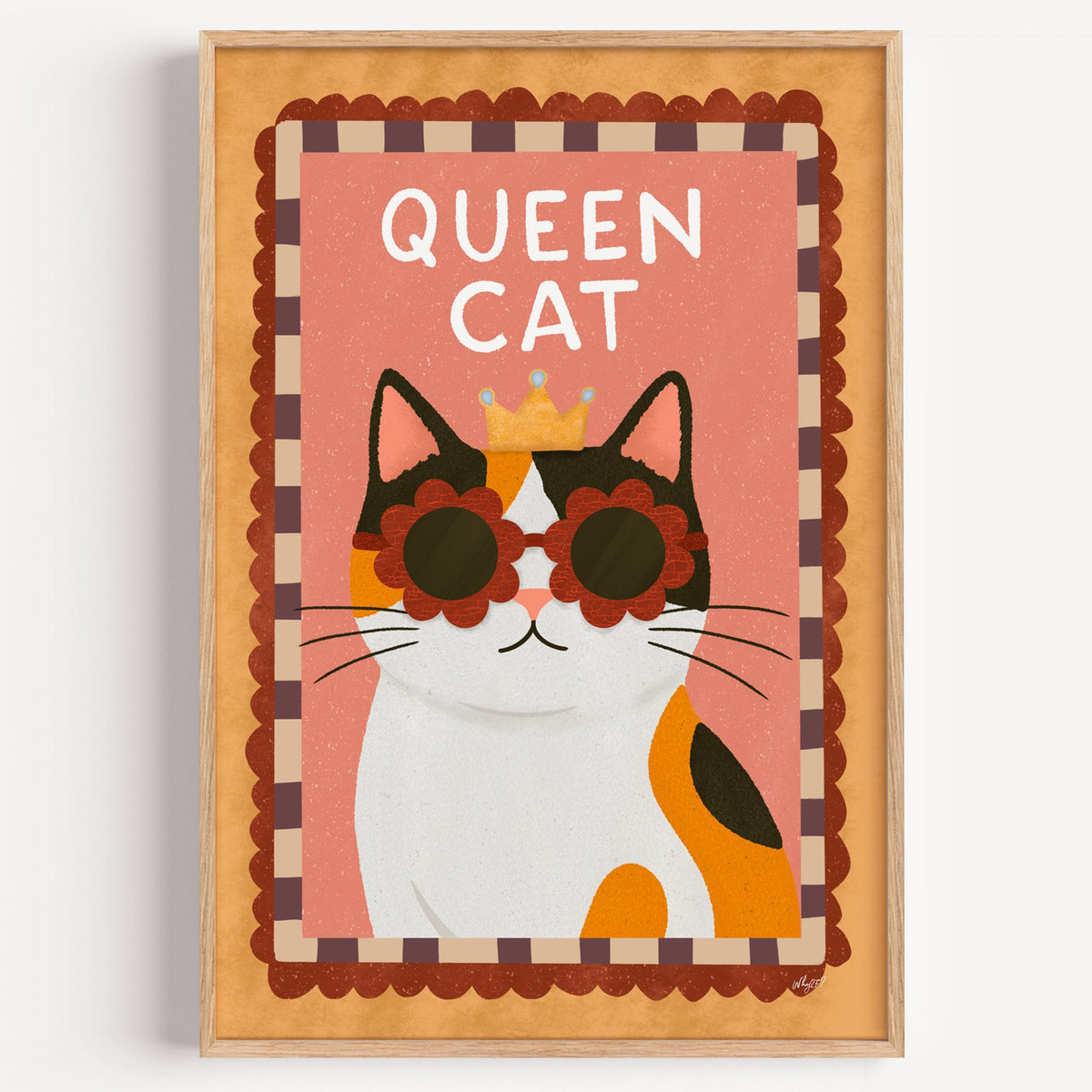 Calico cat with gold crown nursery print in a light oak frame on a plain white wall