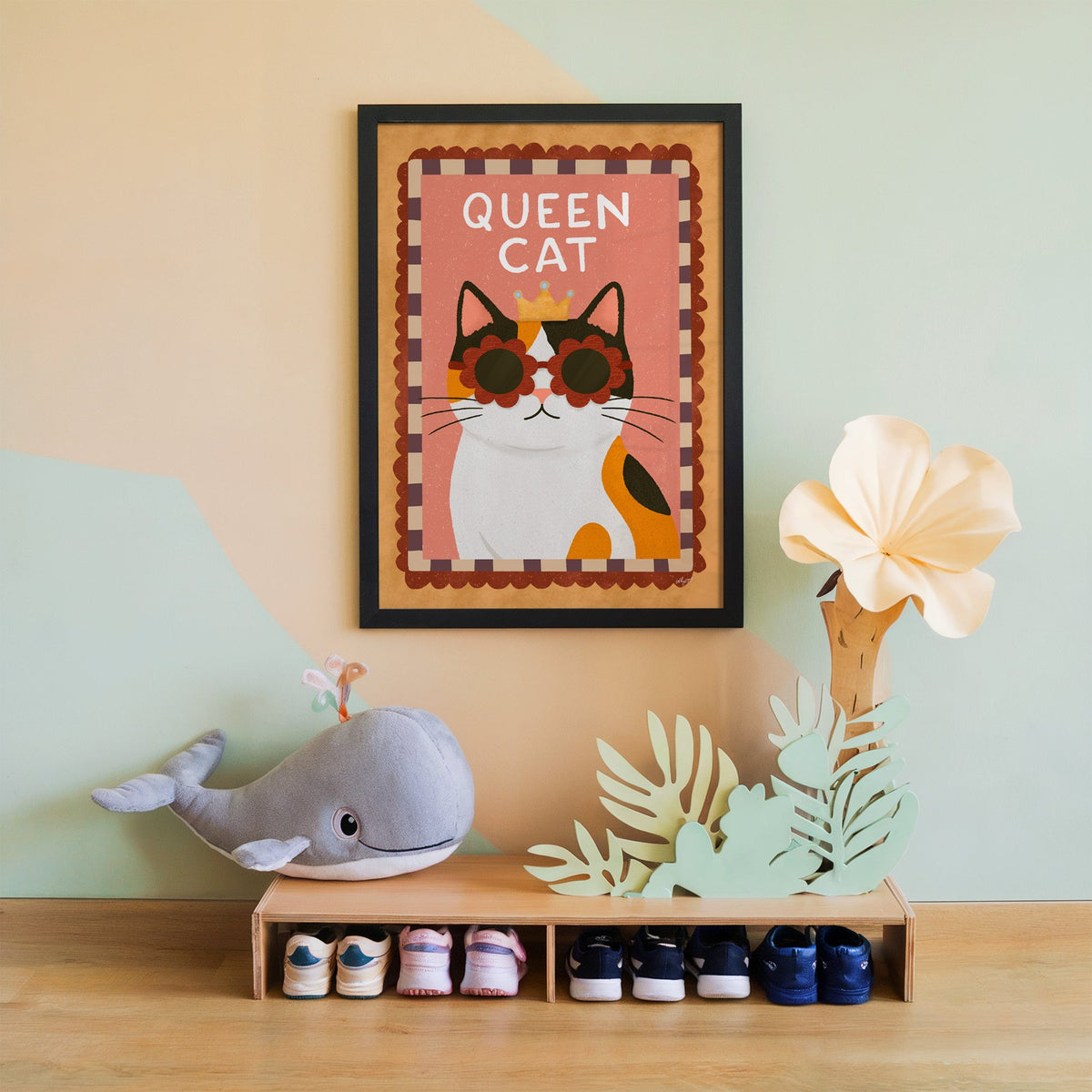 Calico cat with gold crown nursery print in a black frame on a mint and peach wall above a whale plush