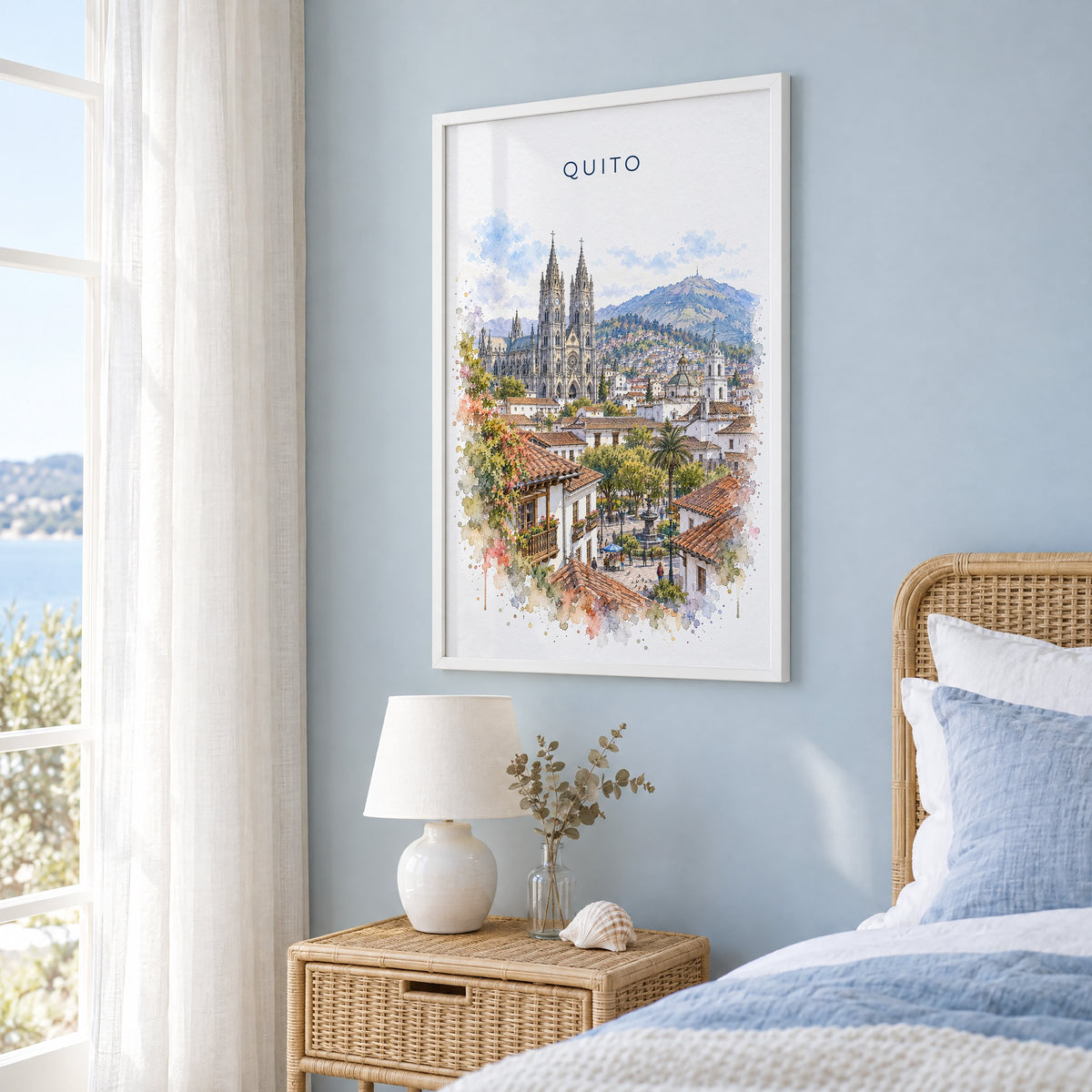 Quito watercolor print in a white frame on a pale blue wall beside a rattan bed in a coastal bedroom