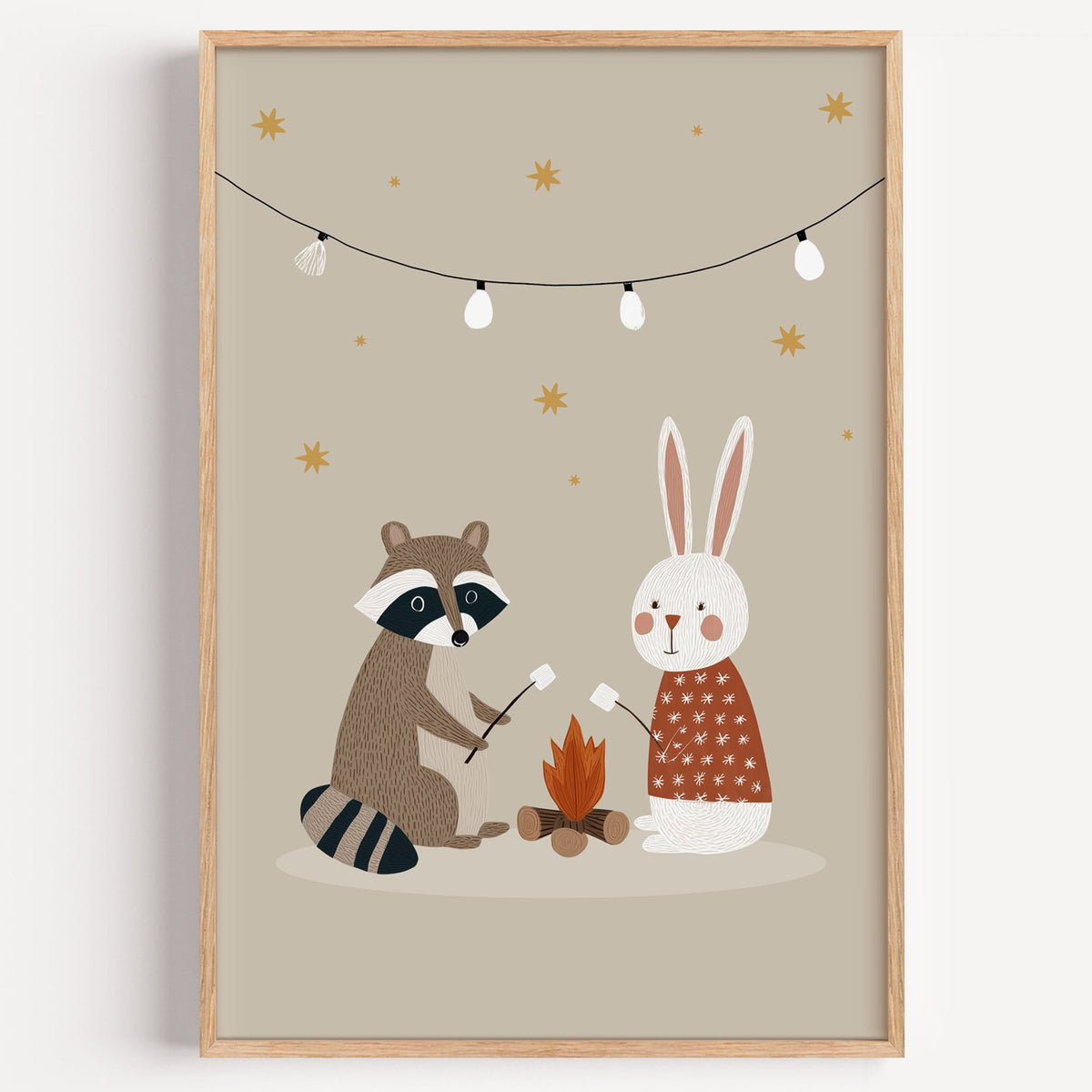 Raccoon and bunny campfire nursery print in a light oak frame on a plain white wall