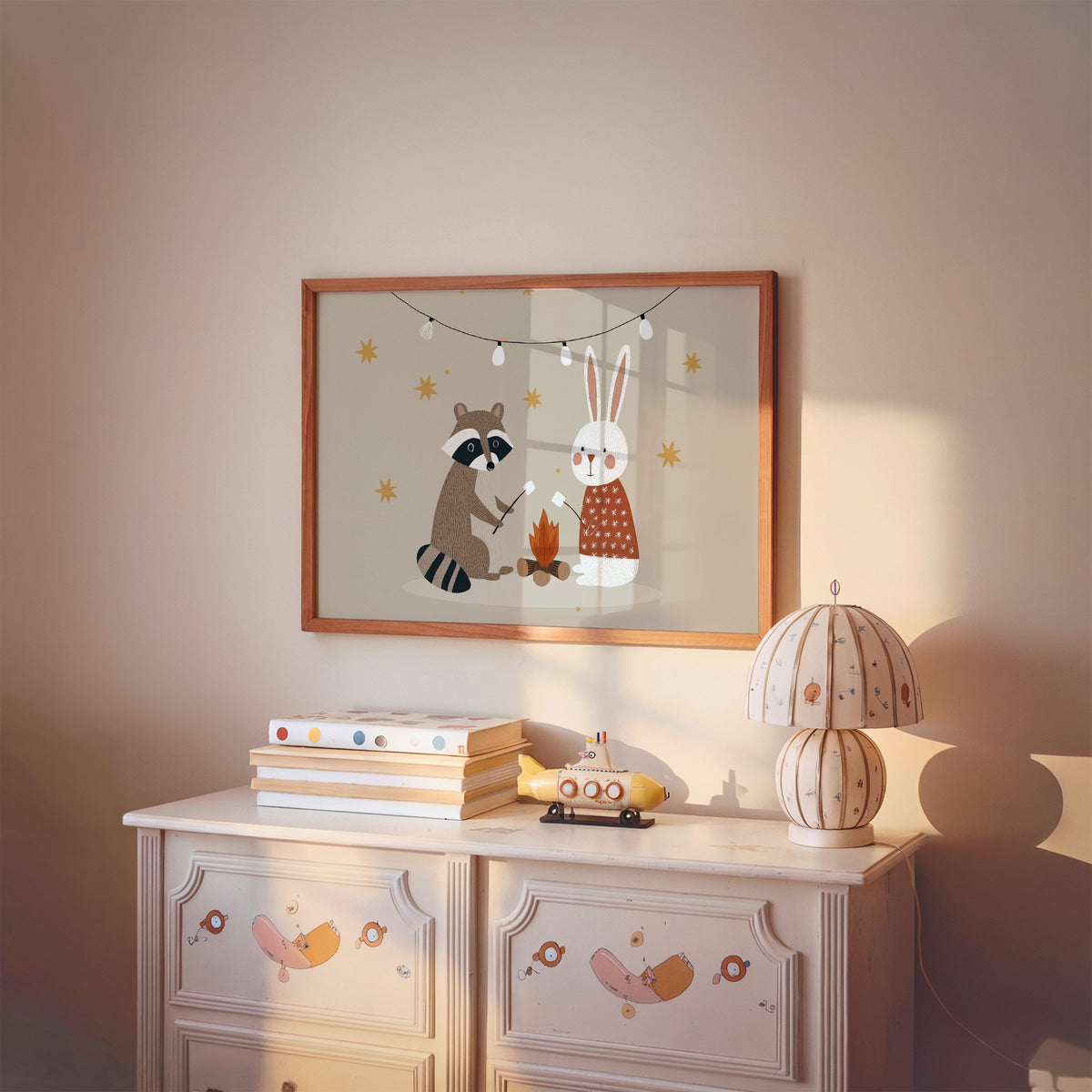 Landscape raccoon and bunny campfire nursery print in a cherry wood frame above a painted dresser and lamp