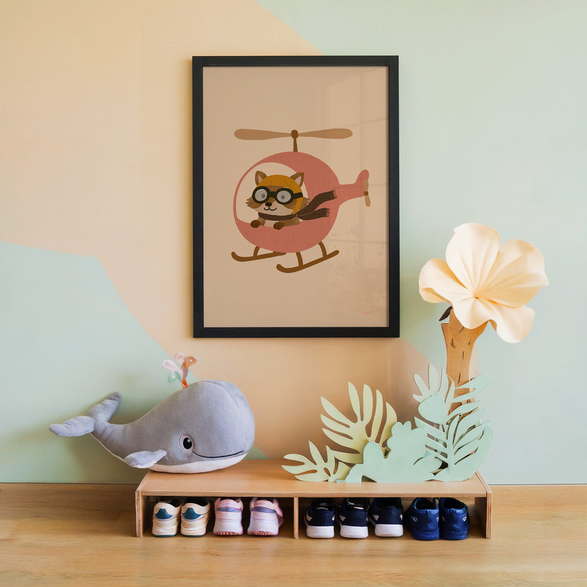 Raccoon pilot in pink helicopter nursery print in a black frame on a mint and peach wall above a whale plush