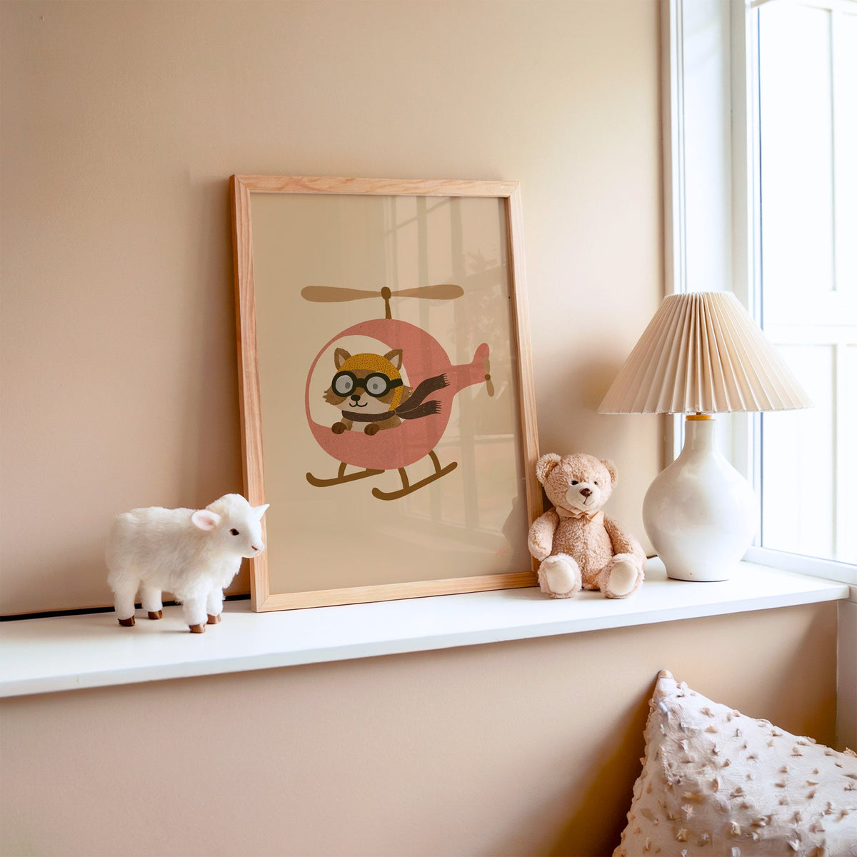 Raccoon pilot in pink helicopter nursery print in an oak frame on a window ledge with a toy lamb and teddy