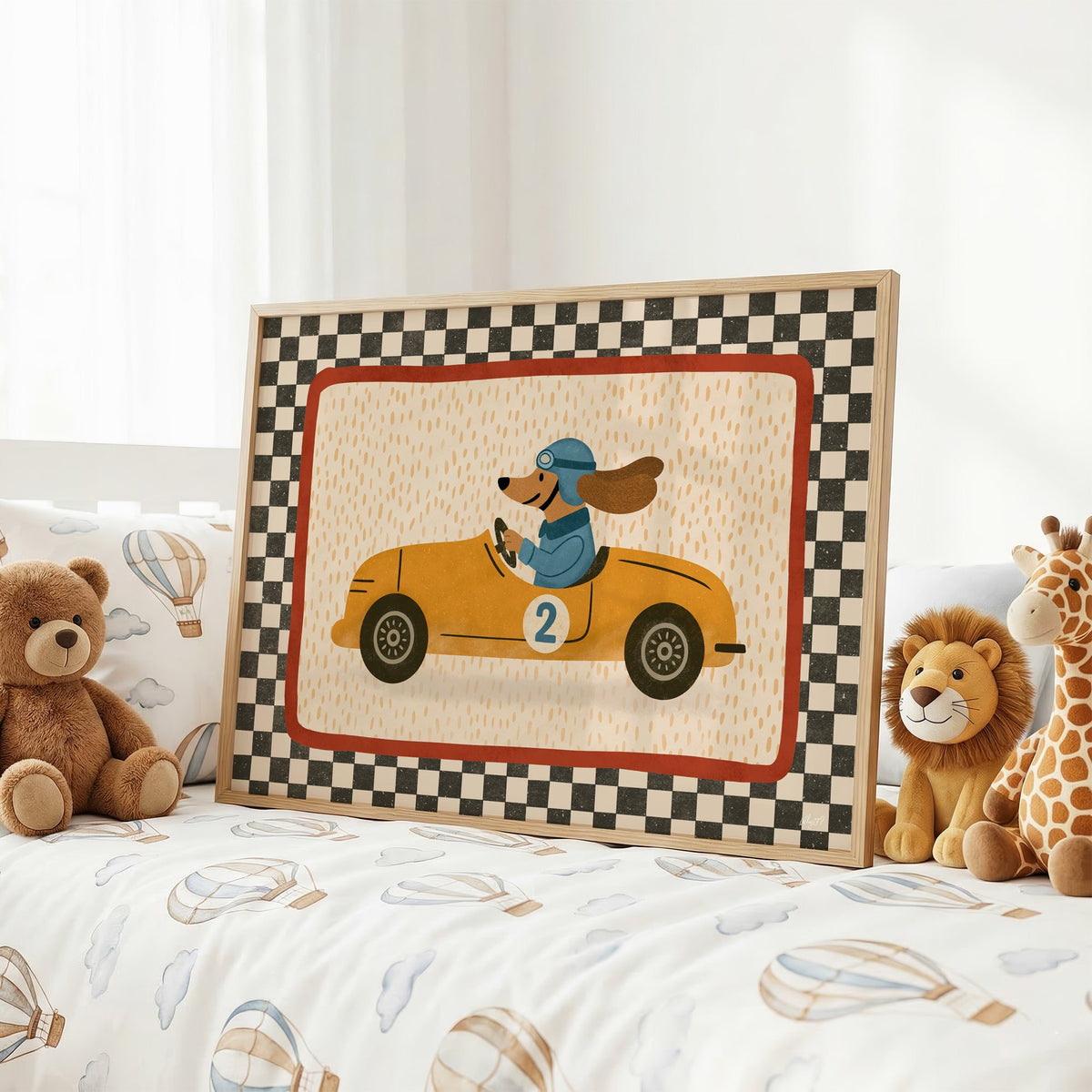 Dog driving yellow race car nursery print in an oak frame on a kids bed with hot air balloon bedding