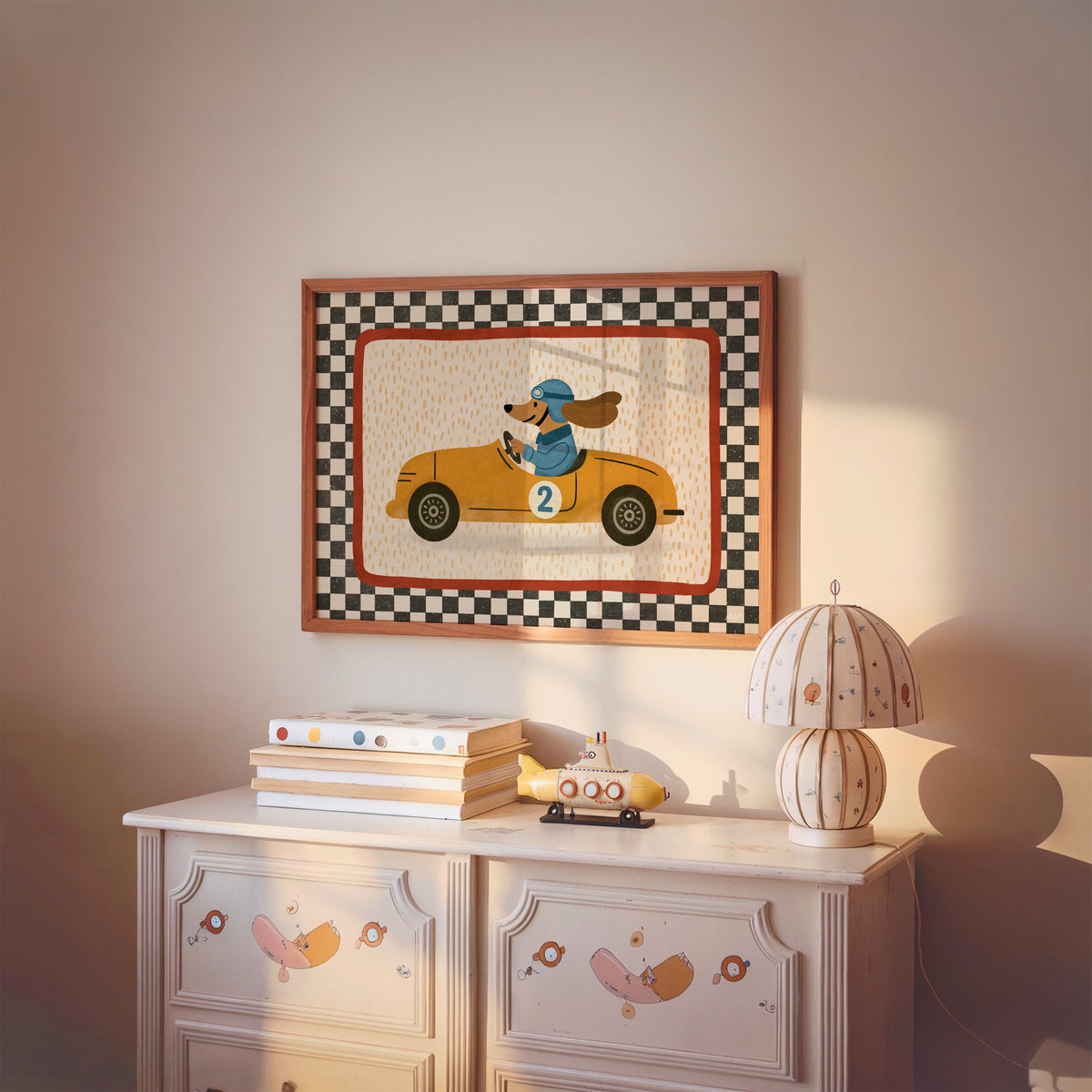 Dog driving yellow race car nursery print in a cherry wood frame above a painted dresser and lamp