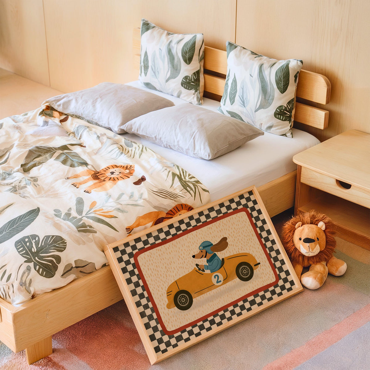 Dog driving yellow race car nursery print in an oak frame leaning on a kids bed by a lion plush