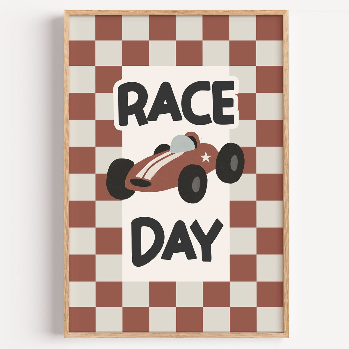 Race day red checkered nursery print in a light oak frame on a plain white wall