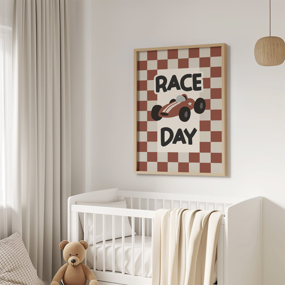 Race day red checkered nursery print in an oak frame above a white crib with a teddy bear