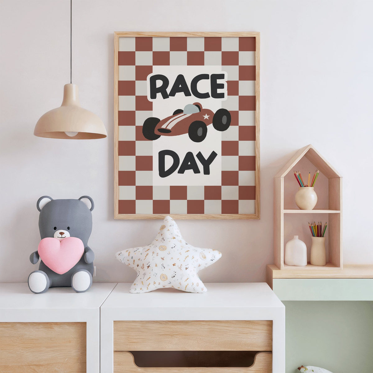 Race day red checkered nursery print in an oak frame above a white dresser with a star pillow and house shelf