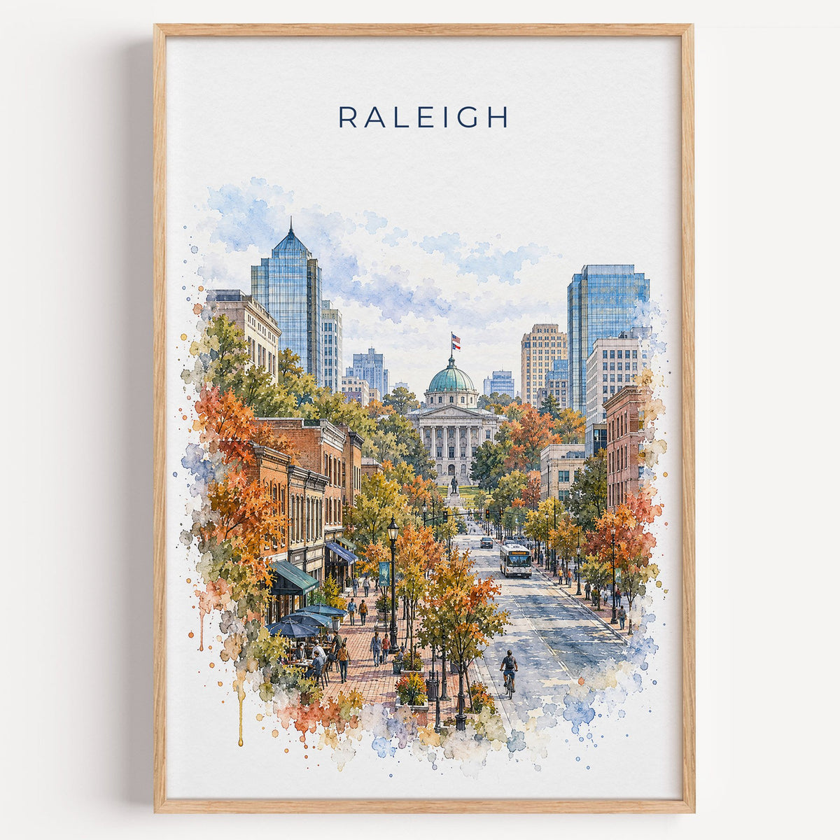 Raleigh watercolor print in a light oak frame on a plain white wall
