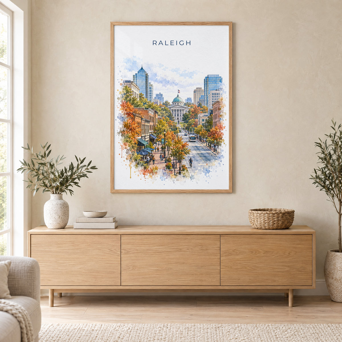 Raleigh watercolor print in an oak frame above a light wood sideboard in a Scandinavian living room