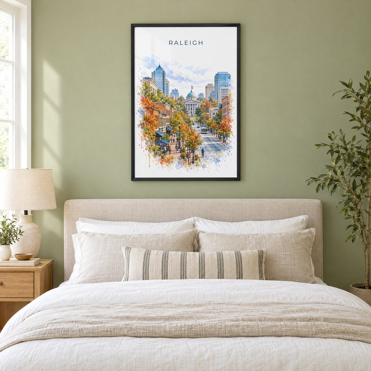 Raleigh watercolor print in a black frame above an upholstered headboard in a sage green bedroom