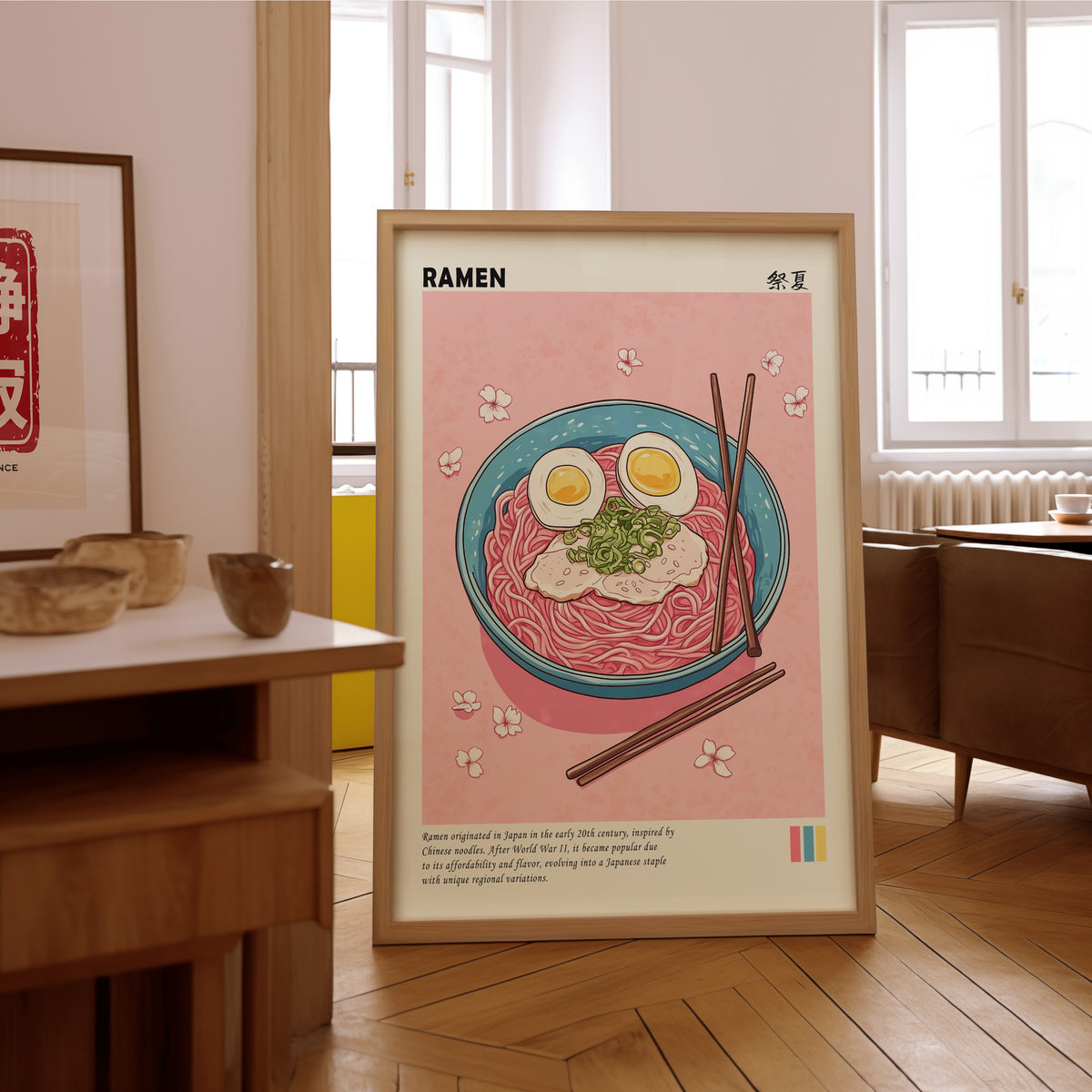 Turquoise ramen bowl with pink noodles print in an oak frame on the parquet floor of a sunlit living room