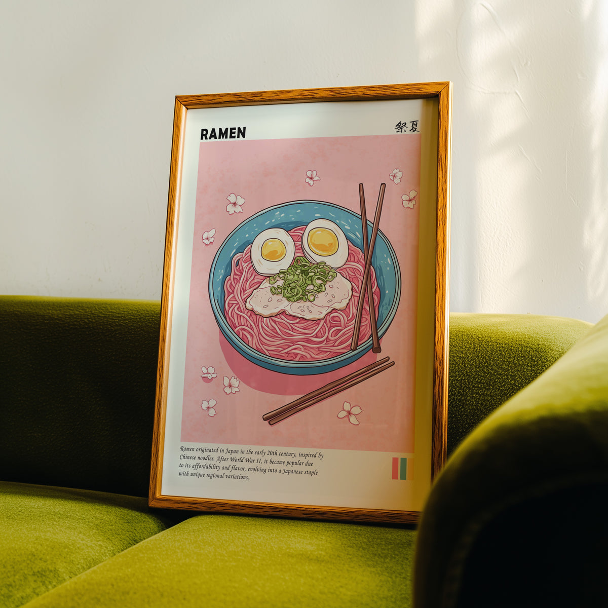 Turquoise ramen bowl with pink noodles print in an oak frame propped on a green velvet sofa
