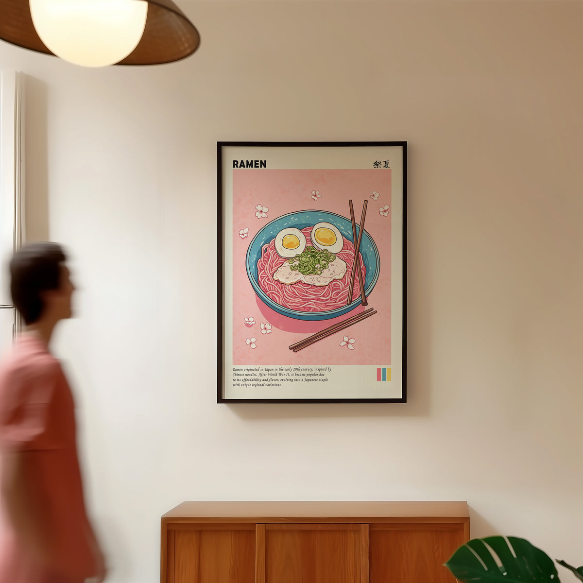 Turquoise ramen bowl with pink noodles print in a black frame in a hallway under a rattan pendant