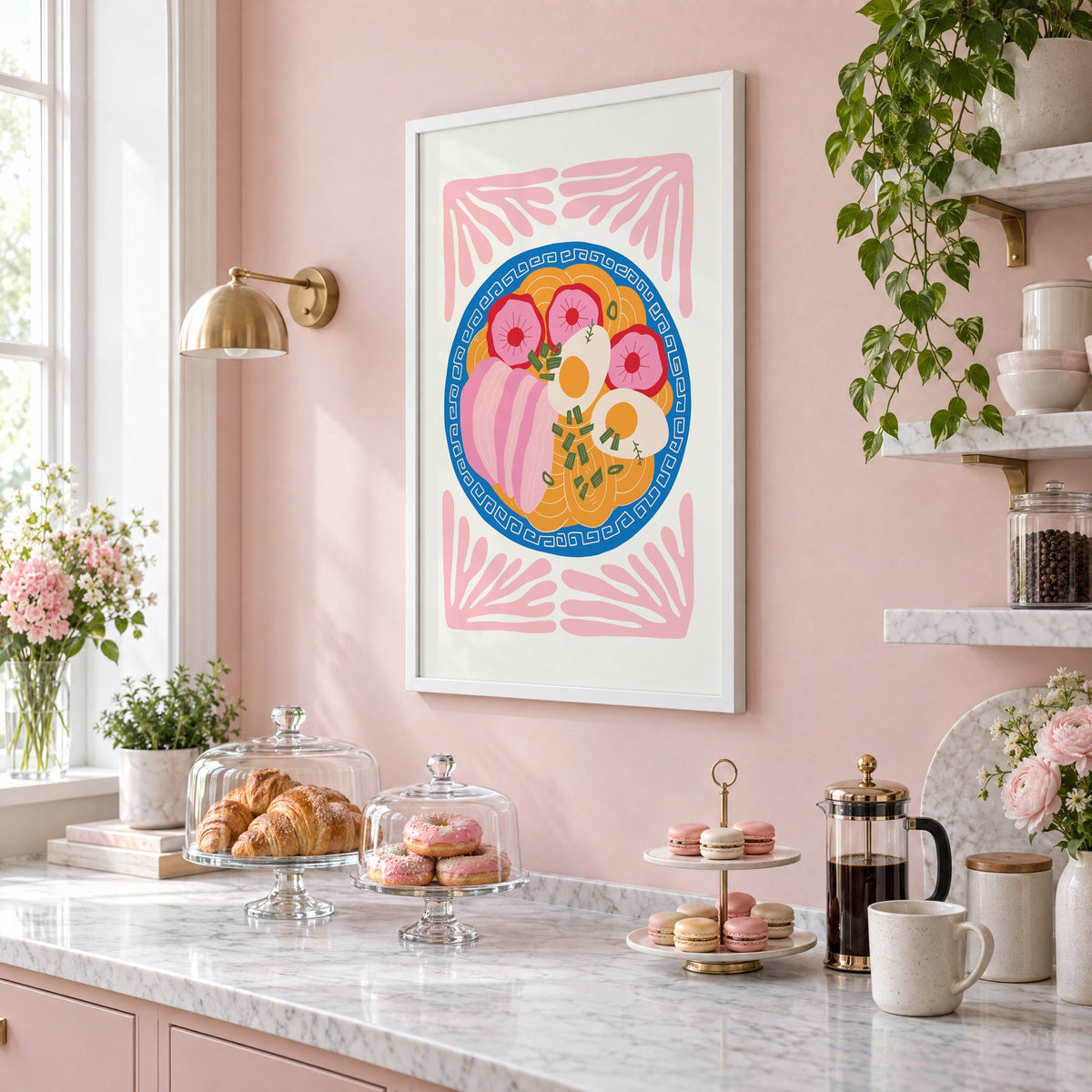 ramen bowl top view pink leaf frame print in a white frame on a blush pink wall above a patisserie counter with croissants and macarons, seen at an angle