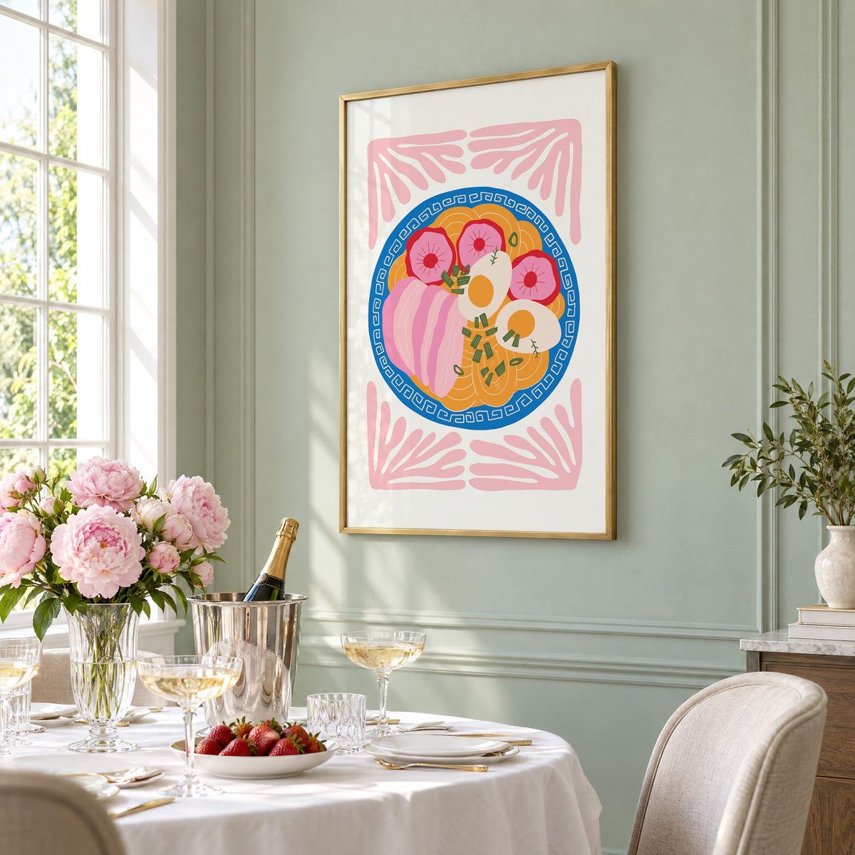 ramen bowl top view pink leaf frame print in a brass frame on a sage wall above a brunch table with champagne and peonies, seen at an angle
