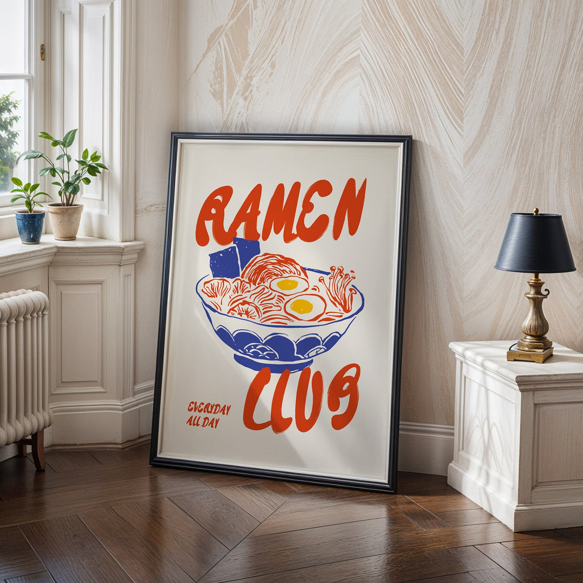 Ramen Club print in a black frame on a dark herringbone floor beside a radiator
