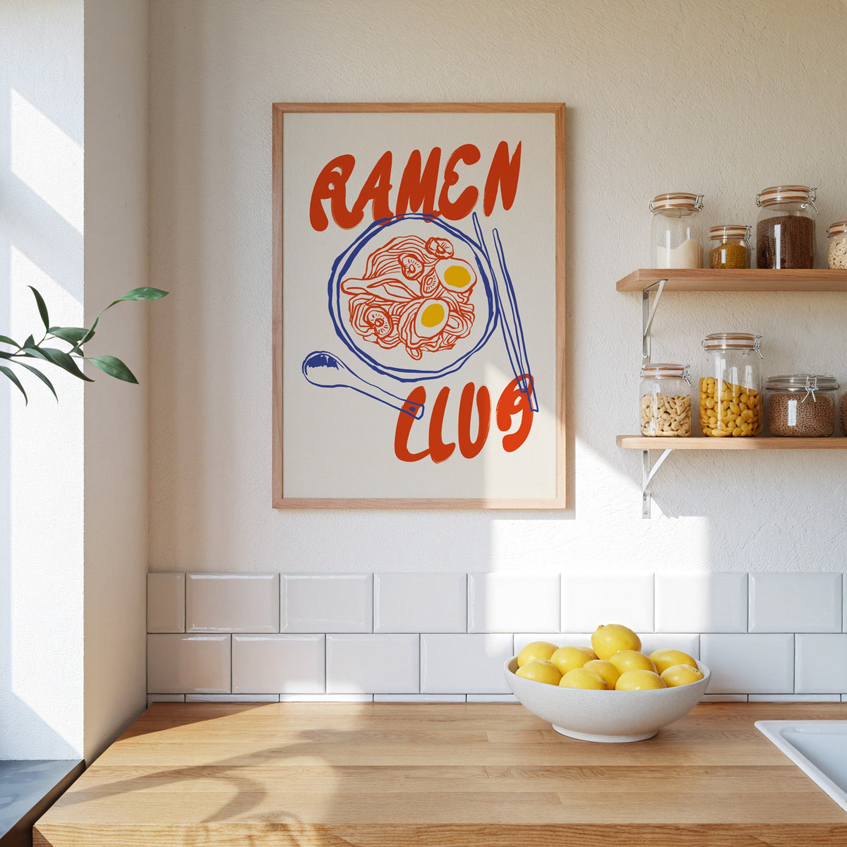 Ramen Club red and blue print in an oak frame beside open kitchen shelves