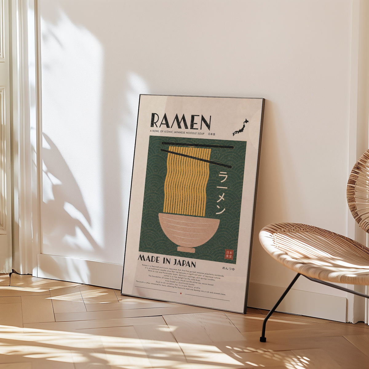 ramen noodles on green wave panel print in a black frame leaning on a herringbone floor beside a woven rattan chair