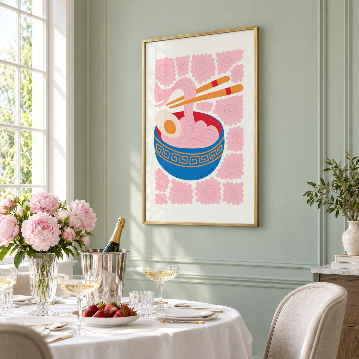 ramen noodles chopsticks pink swirl print in a brass frame on a sage wall above a brunch table with champagne and peonies, seen at an angle