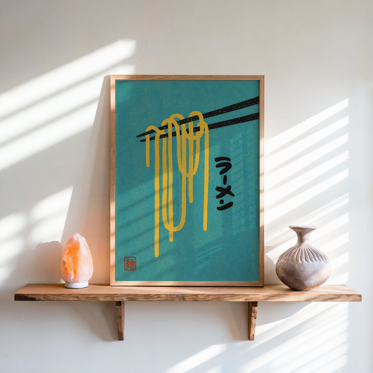 ramen noodles and chopsticks on teal print in an oak frame on a live-edge wall shelf with a salt lamp and clay vase