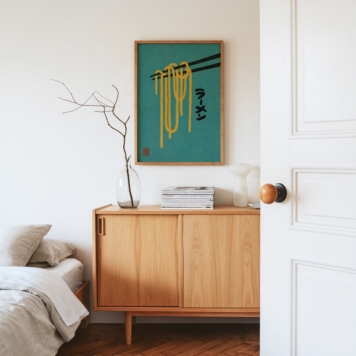 ramen noodles and chopsticks on teal print in an oak frame above an oak sideboard in a bedroom with linen bedding