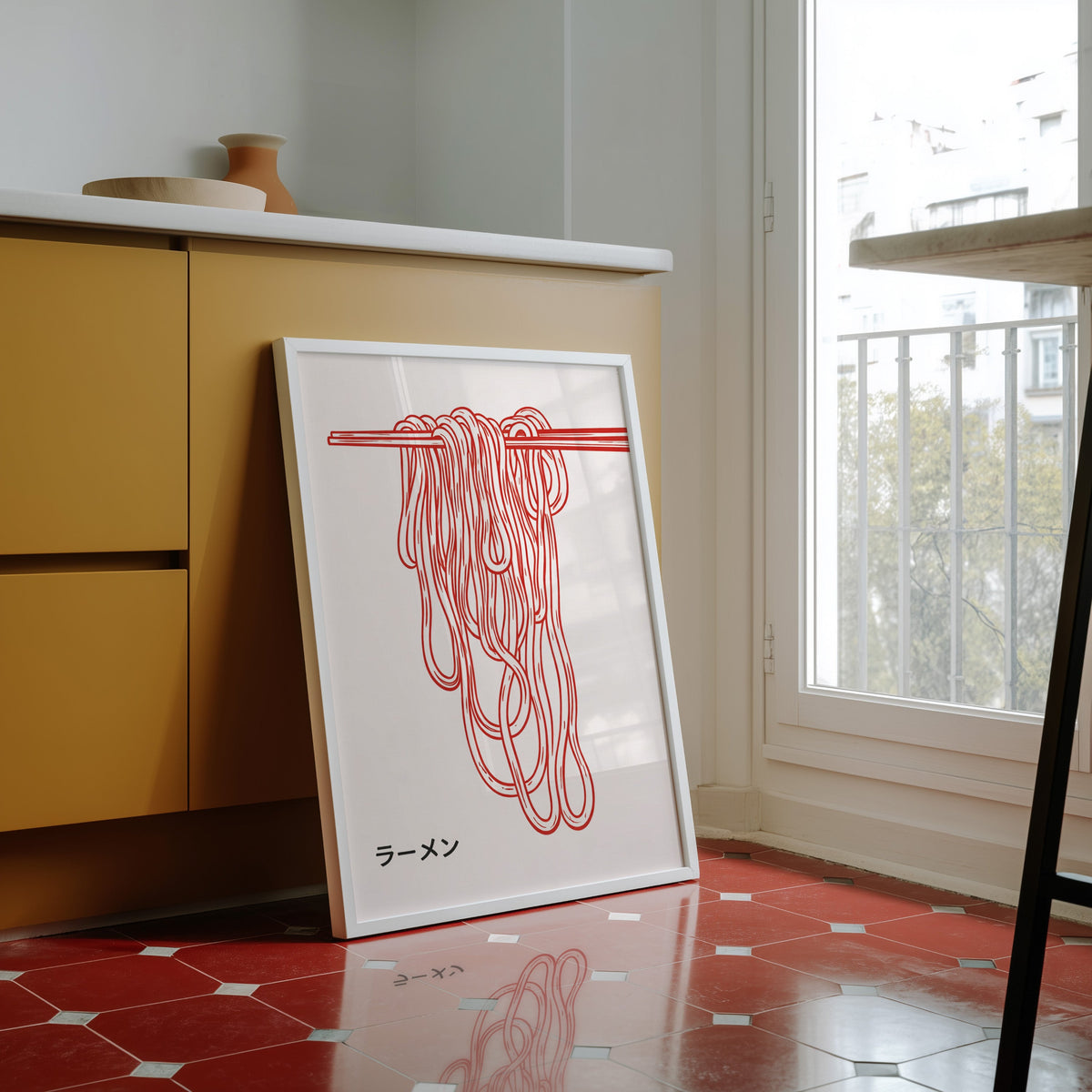 Ramen noodles print in a white frame against yellow cabinets on a red tiled floor