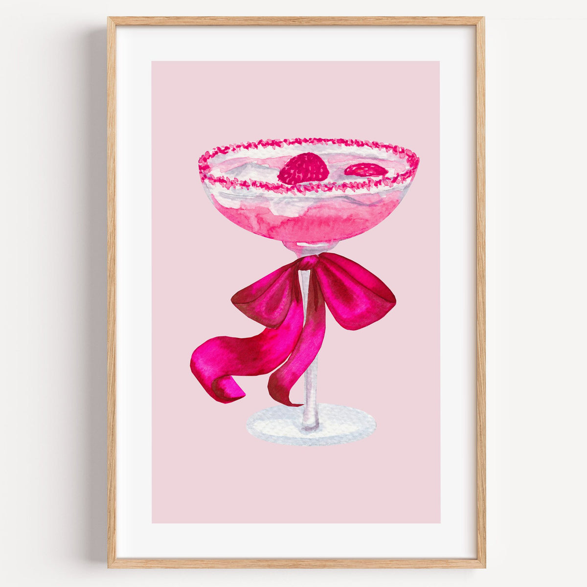 raspberry coupe magenta bow watercolor print in a light oak frame on a plain white wall