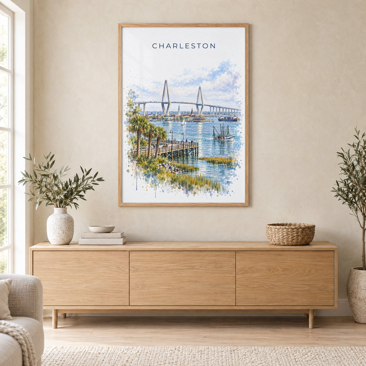 Ravenel Bridge Charleston watercolor print in an oak frame above a light wood sideboard in a Scandinavian living room