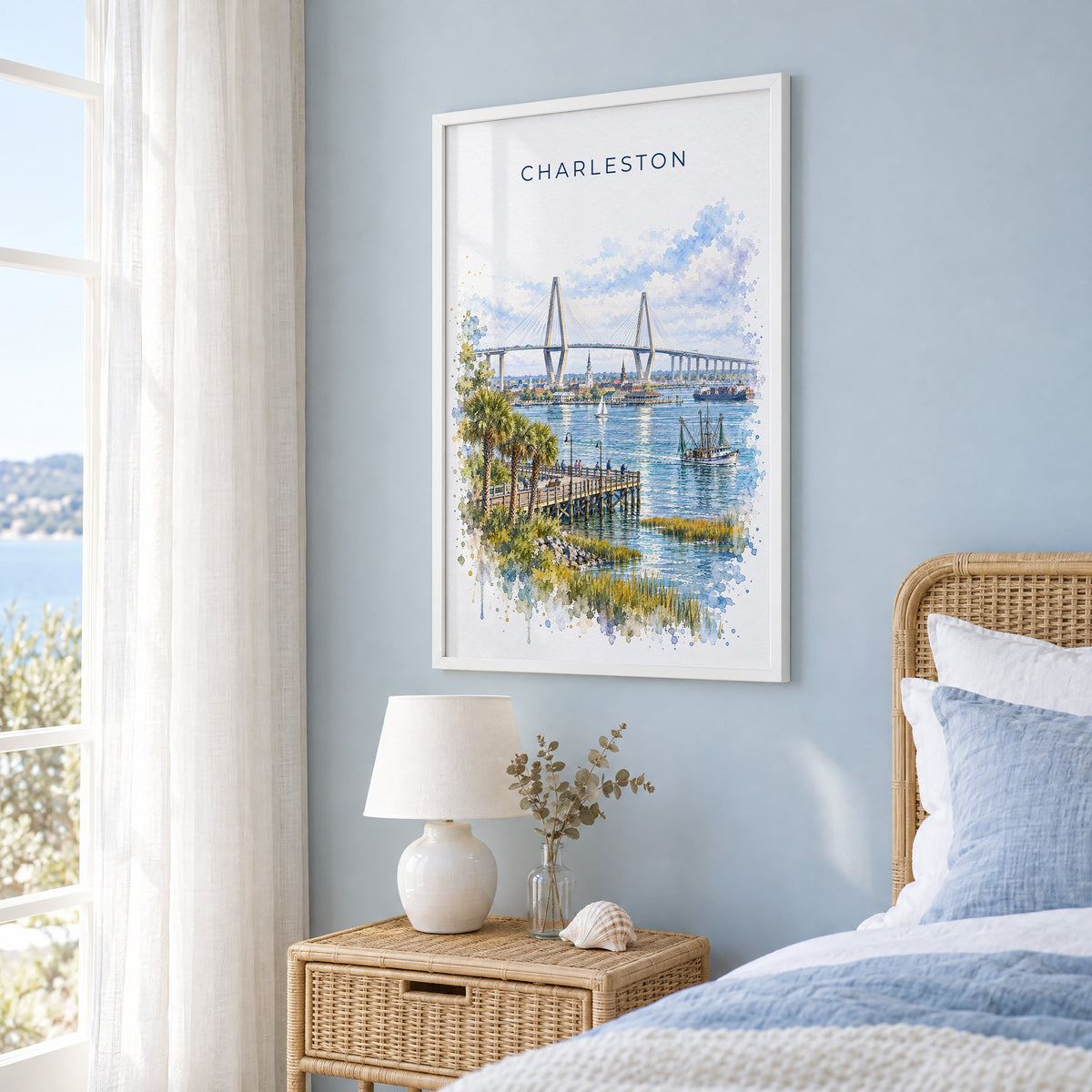 Ravenel Bridge Charleston watercolor print in a white frame on a pale blue wall beside a rattan bed in a coastal bedroom