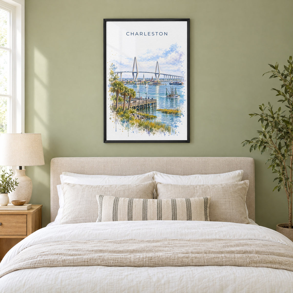 Ravenel Bridge Charleston watercolor print in a black frame above an upholstered headboard in a sage green bedroom