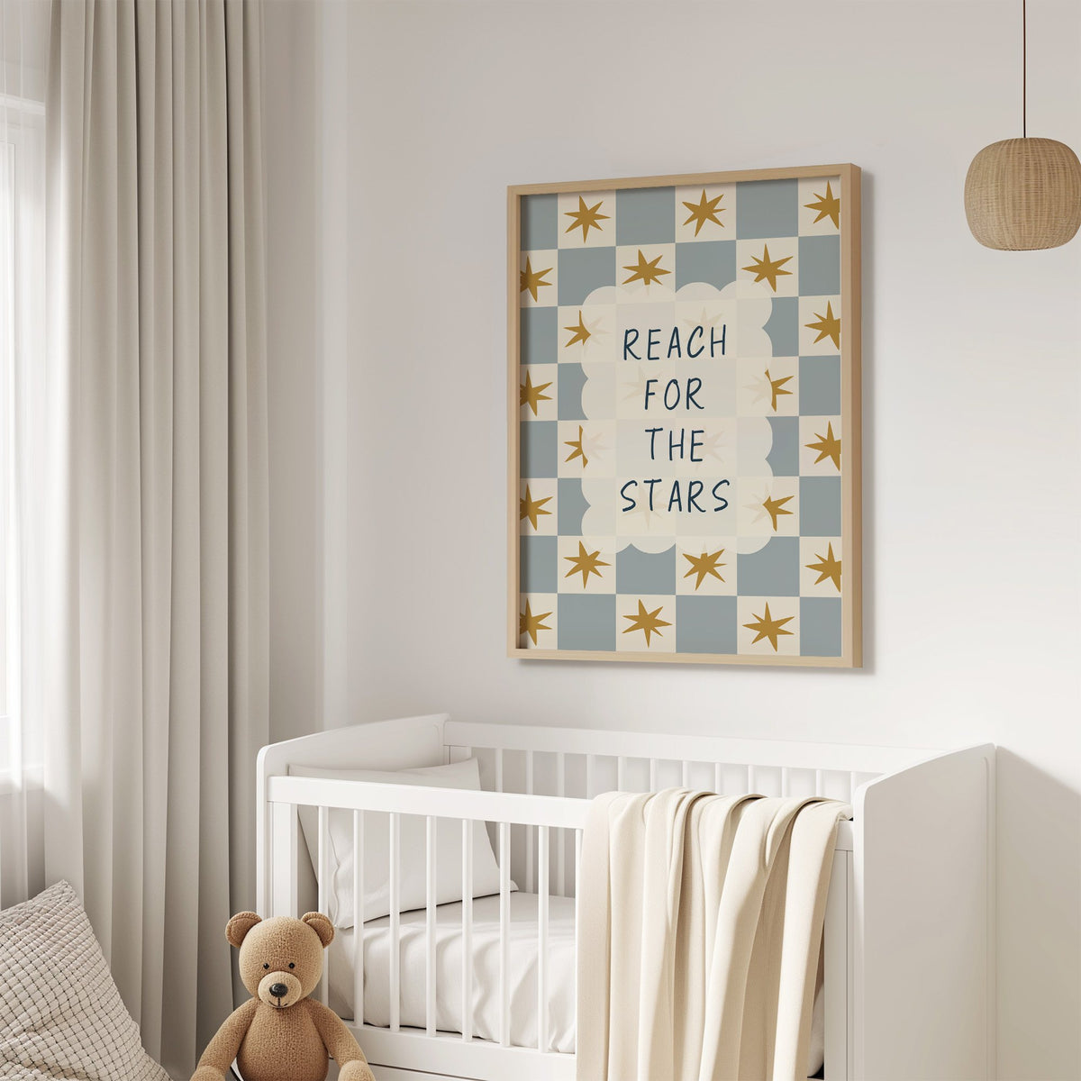 Reach for the stars cloud nursery print in an oak frame above a white crib with a teddy bear