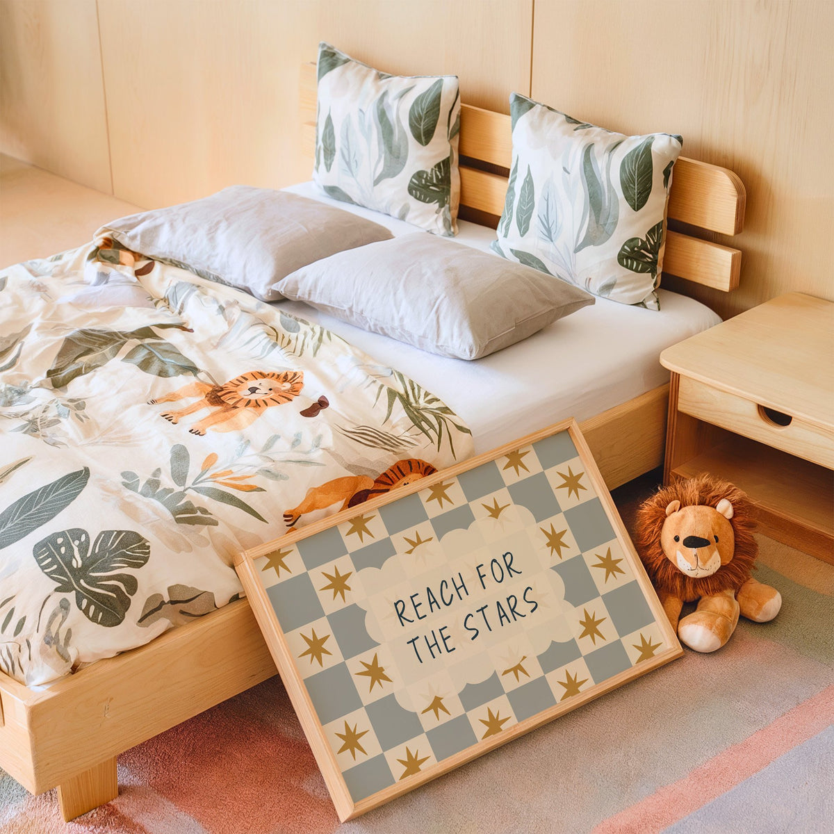 Landscape reach for the stars cloud nursery print in an oak frame leaning on a kids bed by a lion plush